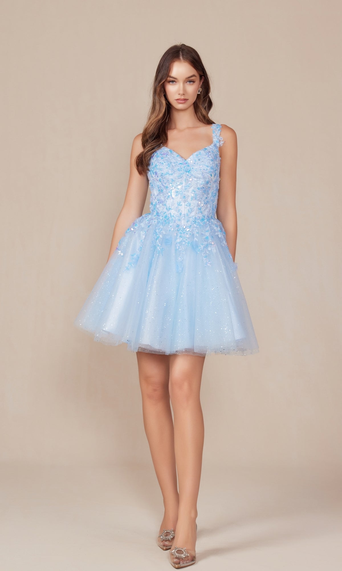 A woman poses against a beige background in the Embroidered-Bodice Short A-Line Hoco Dress H846, featuring floral embellishments, a lace sweetheart bodice, sparkly tulle, and clear heels.